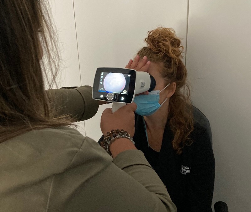 A patient has her eyes screened by a handheld device