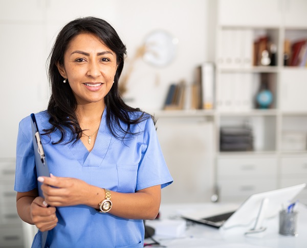 A smiling female health care worker wearing a blue top