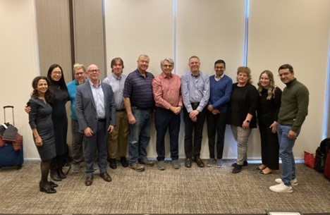 A photo of twelve people standing in a room together.