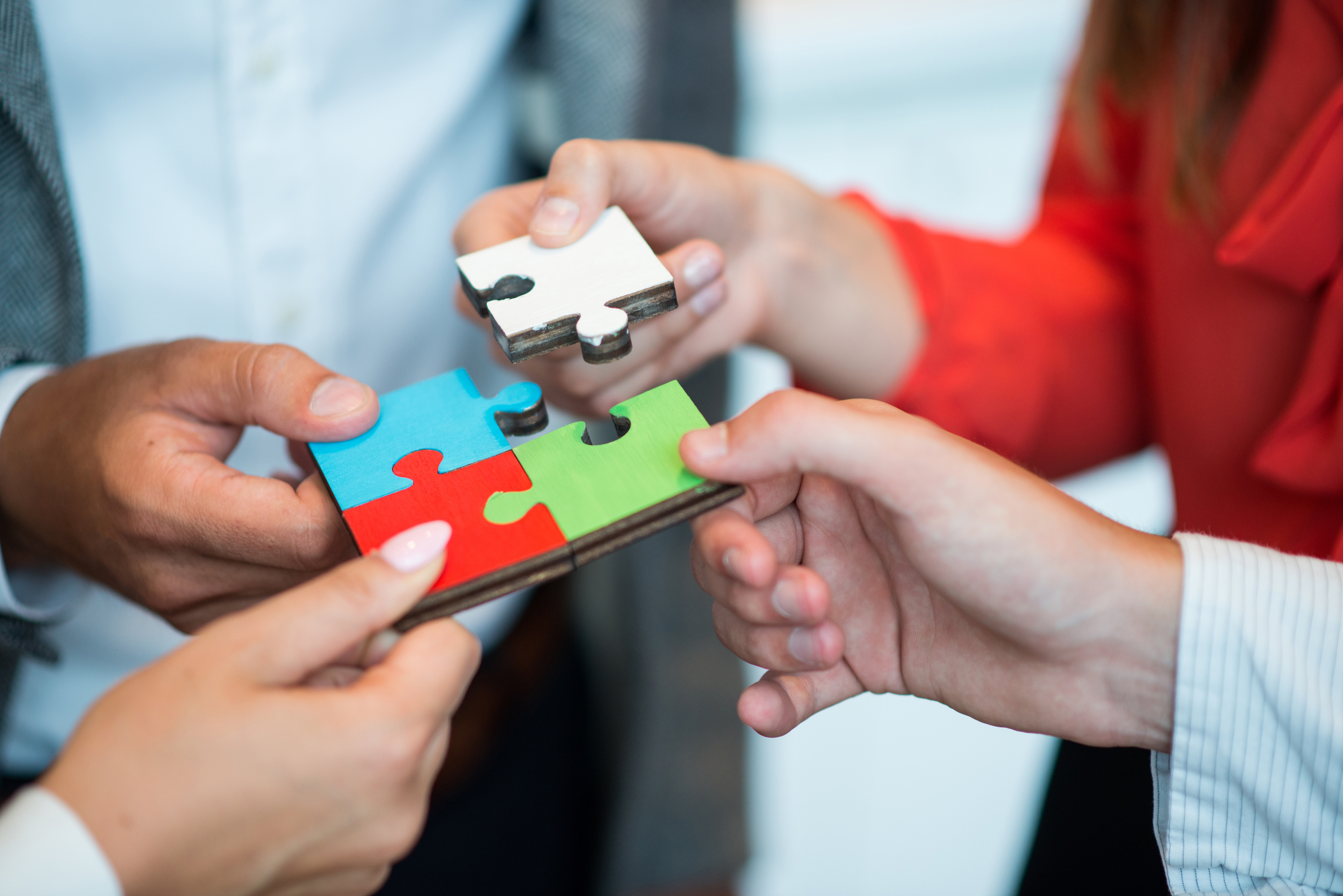 Le travail d'équipe et la collaboration sont symbolisés par quatre mains reliant des pièces d’un casse-tête colorées.