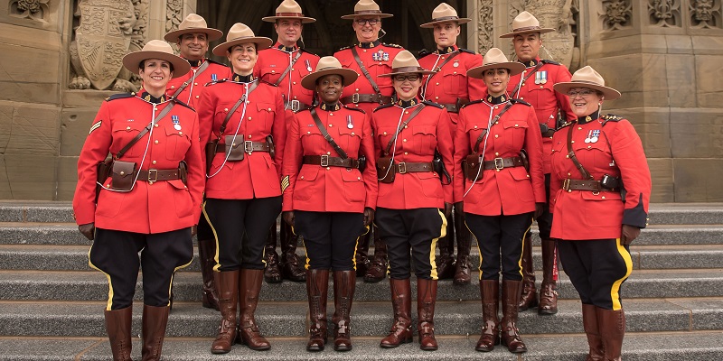 Royal Canadian Mounted Police officers wearing their iconic red coats stand in front of a building