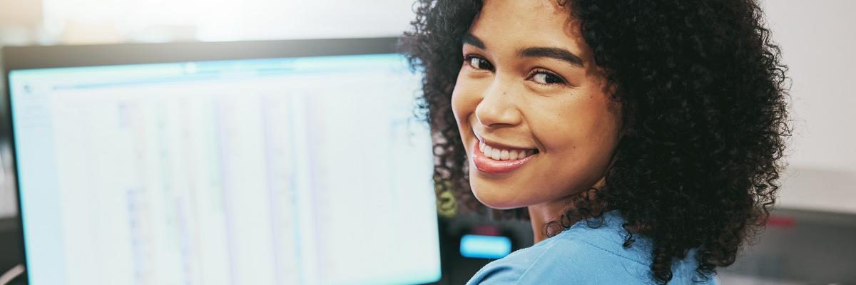 A young female medical receptionist working at the computer and smiling