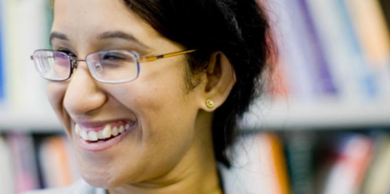 Head shot of a university-aged woman with library stacks behind her.