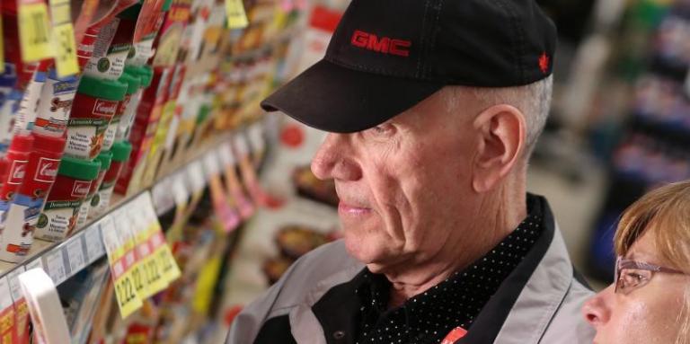 An older man and younger woman looking at price tags in a grocery store