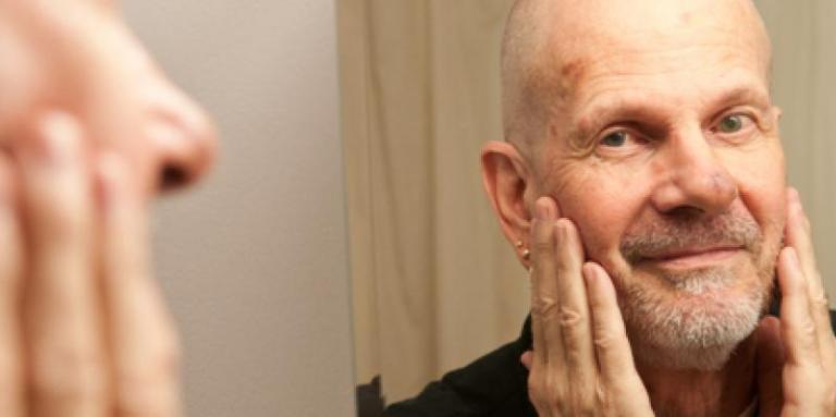 Bald gentleman with goatee looking in mirror.